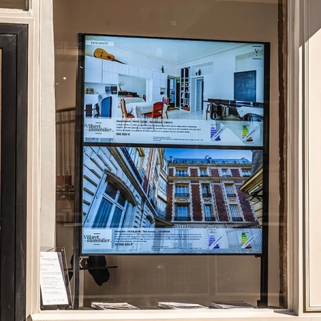 Dwa monitory LCD w witrynie biura nieruchomości